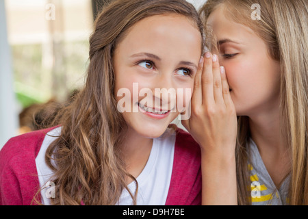 Close-up of two girls whispering dans une école Banque D'Images