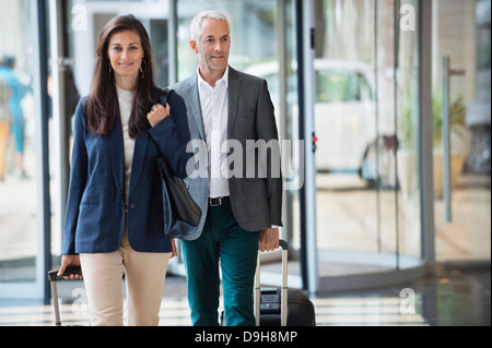 Business couple pulling valises dans un hall de l'hôtel Banque D'Images