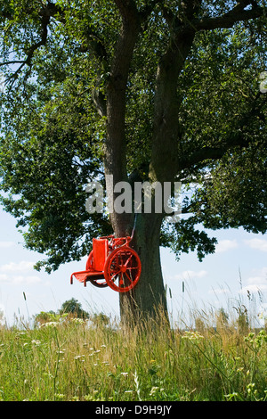 Chaise de roue dans un arbre comme un avertissement pour les motocyclistes déménagement trop rapidement, un fauteuil roulant à un arbre ace un avertissement pour voyager trop un Banque D'Images