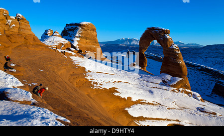 Des groupes de personnes regardant Delicate Arch avec de la neige en hiver au coucher du soleil, Arches National Park, Utah, United States of America Banque D'Images