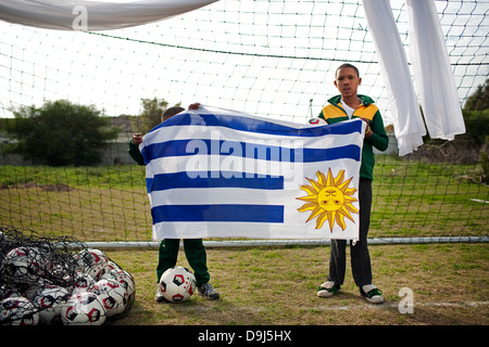 Un portrait deux jeunes enfants à l'école tenant un drapeau Uruguay H P Williams dans les écoles de football Stompneus Bay à Western Cape Banque D'Images