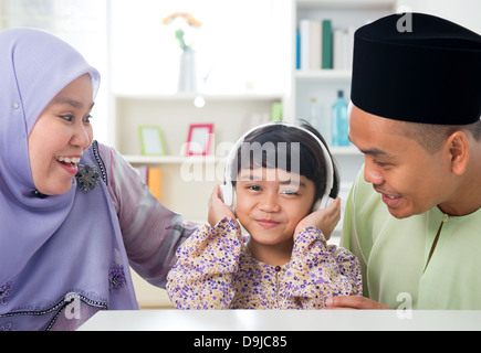 Jeune fille musulmane d'écouter de la musique à la maison. Mode de vie de la famille de l'Asie du Sud-Est. Happy smiling parents malais et de l'enfant. Banque D'Images