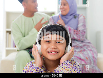 Jeune fille musulmane à l'écoute de chanson à la maison. Mode de vie de la famille de l'Asie du Sud-Est. Happy smiling parents malais et de l'enfant. Banque D'Images