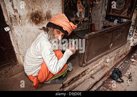 À propos de l'homme pour fumer une biri (Indian cigarett) dans l'étroite rue de Varanasi, Benares, Uttar Pradesh, Inde Banque D'Images