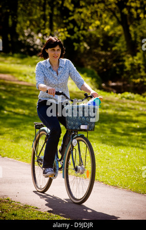 Jeune femme caucasienne vêtue à la légère, à vélo dans un parc britannique Banque D'Images