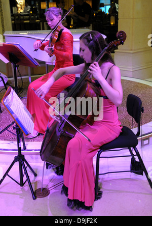 Dame musiciens jouent. Robe rouge profond et moody éclairage magenta sur les sujets. Banque D'Images