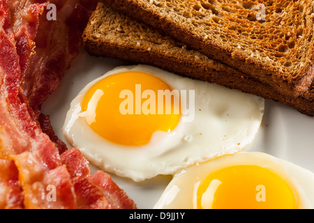 Sunnyside organiques jusqu'Œuf avec du pain grillé et du bacon pour le petit déjeuner Banque D'Images