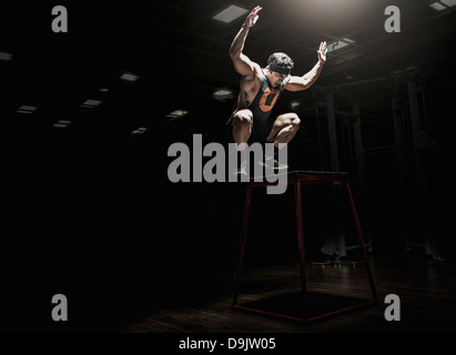 Jeune homme sautant in gym Banque D'Images