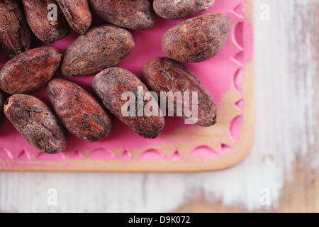 Chocolat cacao torréfié haricots sur fond de bois blanc et rose Banque D'Images