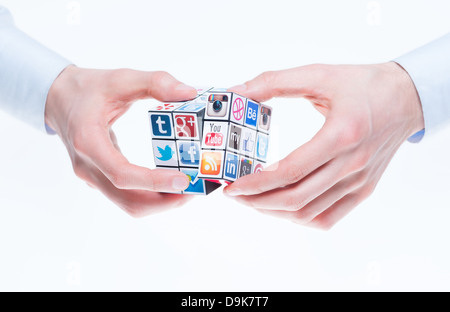 Mains tenant un rubiks cube avec des logos de marques de médias sociaux. Banque D'Images