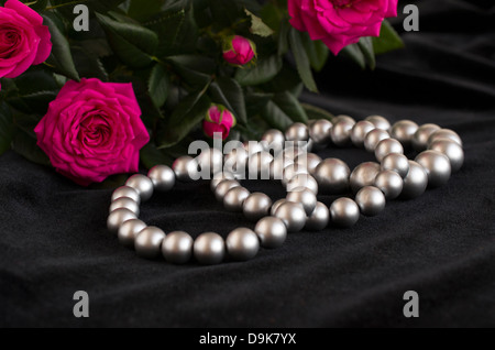 Cloche en bronze antique et bouquet de roses bracelets de perles et bouquet de roses sur fond noir Banque D'Images