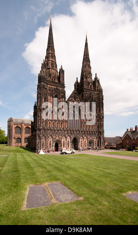 Avant de l'ouest de la cathédrale de Lichfield de St Chad avec voiture de mariage vintage Wolsley et mariée en robe blanche tombe en premier plan Banque D'Images