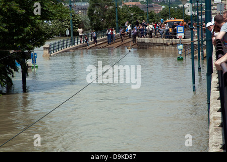 Les spectateurs et les touristes sur le bord de voies de tram en partie submergé sur l'explosion des rives du Danube, Budapest, Hongrie Banque D'Images