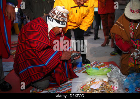 LA PAZ, BOLIVIE, 21st juin. Un mâle Aymara amauta ou chef spirituel frotte la graisse de lama sur un foetus de lama (appelé sullu / suyu localement) tout en préparant une offre spéciale appelée Mesa blanca pour un événement pour célébrer Aymara nouvel an ou Willka Kuti (également le solstice d'hiver, 21 de Junio). Le lever du soleil marque le début de la nouvelle année (5521 dans le calendrier Aymara). Le shaman porte un chapeau de laine avec des rabats d'oreille appelés un chullo / chullu et un poncho rayé rouge et noir typique des régions altiplano de Bolivie. Credit: James Brunker Alay Live News Banque D'Images