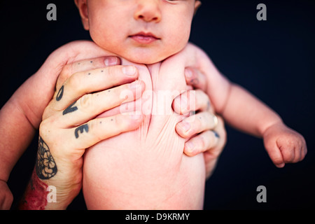 Père avec mains tatouées holding baby boy Banque D'Images