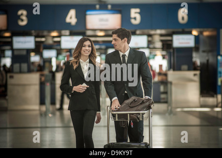 Businesspeople in airport avec chariot à bagages Banque D'Images