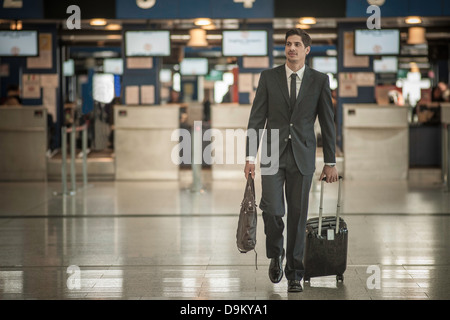 Jeune homme à la valise à roulettes in airport Banque D'Images