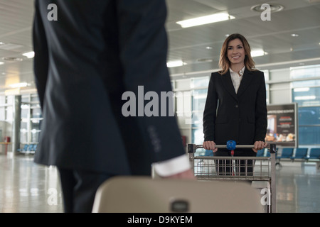 Businesspeople in airport avec chariot à bagages Banque D'Images