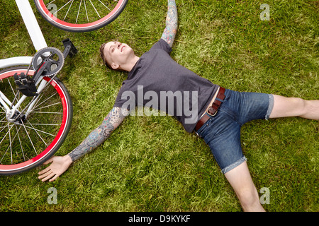 Les jeunes tattooed man lying on grass Banque D'Images