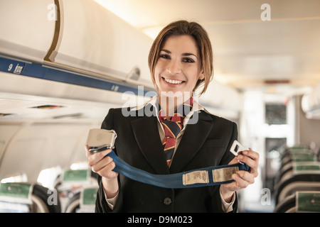 Hôtesse de l'air l'exécution de la démonstration de la sûreté on airplane Banque D'Images