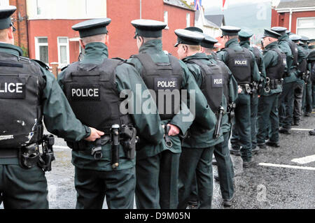 Les agents de police PSNI en uniforme portant des gilets haute visibilité forment une ligne à travers une route pour empêcher une foule de procéder Banque D'Images