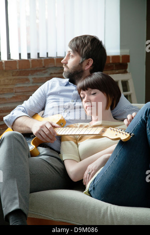 Jeune femme dormir à côté de musicien sur canapé Banque D'Images