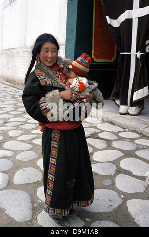 Femme tibétaine avec son tout-petit dans le comté de Tongren connus pour les Tibétains que Rebgong dans la préfecture autonome tibétaine de notes dans le Qinghai, Chine Banque D'Images