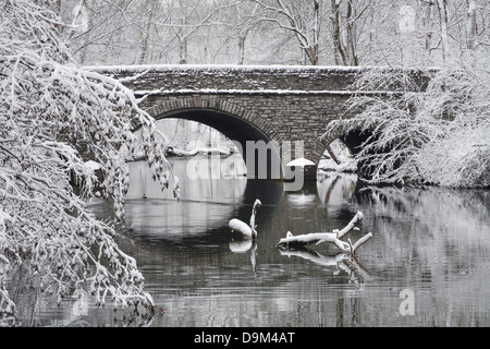 Arbres couverts de neige qui encadrent un pont de pierre et la rivière en hiver, dans le parc, Sharon Woods, le sud-ouest de l'Ohio, USA Banque D'Images