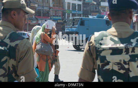 Srinagar Cachemire sous administration indienne, 22 juin 2013. Les femmes musulmanes cachemire traverse une route comme policiers indiens montent la garde à côté de l'épars melons près de l'endroit où des militants présumés ont tué leurs deux collègues à Srinagar, la capitale d'été du Cachemire indien.La sécurité a été renforcé au Cachemire, en particulier la ville de Srinagar, capitale d'été, devant le Premier Ministre indien Manmohan Singh à la visite de la région de l'Himalaya. (Sofi Suhail/ Alamy Live News) Banque D'Images