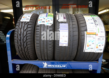 De nouveaux pneus pour la vente sur un rack dans un garage avec des autocollants d'information Andorre Andorre-la-Vieille Banque D'Images