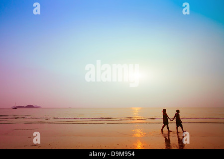 Silhouettes de couple sur la plage au coucher du soleil Banque D'Images