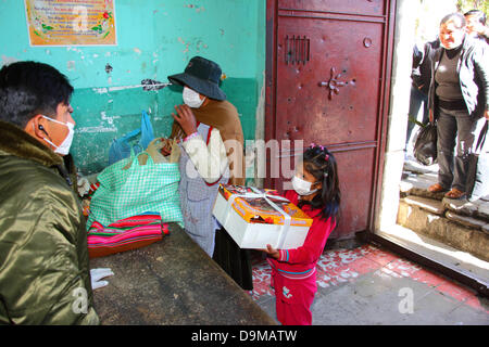 La Paz, Bolivie.22 juin 2013.Une fille attend avec un gâteau d'anniversaire tandis que la police fout les effets de sa mère pendant un contrôle de sécurité avant de rendre visite à des parents emprisonnés à la prison de San Pedro. Banque D'Images