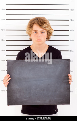 Teenage boy holding un tableau noir mug shot pénales Banque D'Images