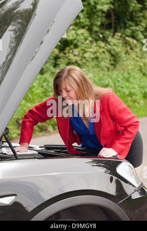 Femme automobiliste avec le capot en place l'inspection du moteur Ministère de sa voiture Banque D'Images