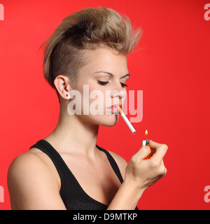 Fashion femme allumer une cigarette avec un fond rouge Banque D'Images