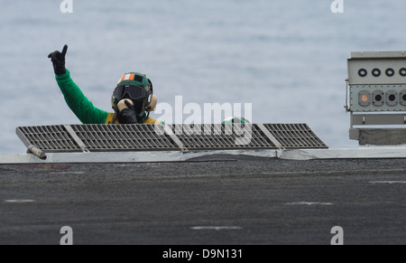 L'Aviation de l'US Navy un maître de Manœuvre donne le signal pendant les opérations de vol sur le pont du porte-avions USS Nimitz 13 juin 2013 dans le golfe d'Oman. Banque D'Images