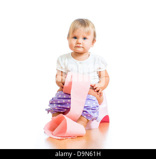 Smiling baby sitting sur pot de chambre avec rouleau de papier toilettes Banque D'Images