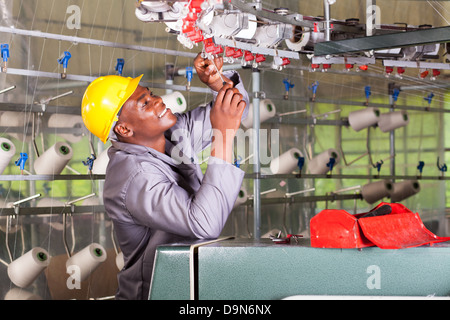 African American textile mechanic repairing tisser Banque D'Images