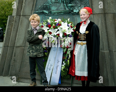 À Reykjavik, sur l'indépendance de l'Islande anniversaire, deux jeunes posent à un mémorial--la fille en costume national et bonnet rouge Banque D'Images