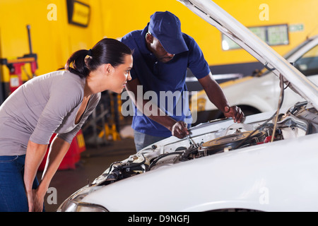 Jeune femme d'envoyer sa voiture pour la réparation en garage Banque D'Images