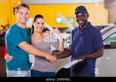 Happy young couple giving thumb up pour atelier de réparation automobile Banque D'Images
