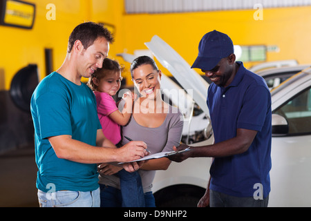 Happy Family man signature facture en atelier de réparation de voiture Banque D'Images