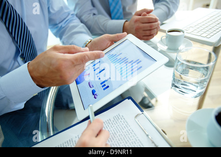 Les gens font des affaires modernes, graphiques et tableaux en démonstration sur l'écran d'un touchpad Banque D'Images