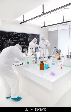 Vue générale de trois personnes d'observer et d'analysig les réactions chimiques dans un laboratoire à l'aide de substances colorées et outils de laboratoire sur un laboratoire Banque D'Images