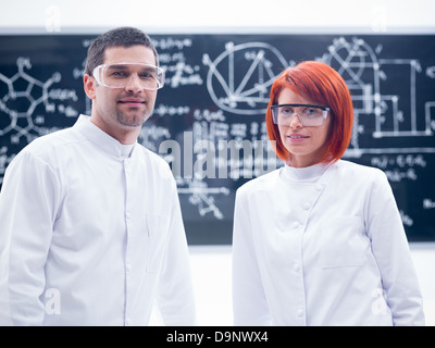 Close-up de deux chercheurs smiling dans un laboratoire de chimie avec un tableau noir sur l'arrière-plan Banque D'Images