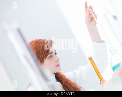 Vue latérale d'une belle jeune fille élève conduire une expérience dans un laboratoire de chimie avec outils colorés Banque D'Images