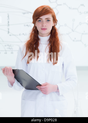 Vue générale d'un élève dans un laboratoire de chimie à la réussite dans l'appareil photo tout en tenant en mains un clip-board et avec une tran Banque D'Images