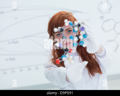 Vue générale d'un élève dans un laboratoire de chimie à la recherche dans l'appareil photo et tenant en mains et d'analyser et d'un modèle moléculaire DMT Banque D'Images