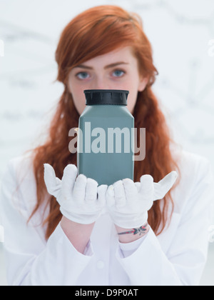 Close-up d'un élève dans un laboratoire de chimie à la recherche dans l'appareil photo et tenant dans les mains et l'analyse d'un destinataire gris Banque D'Images