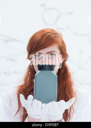 Vue générale d'un élève dans un laboratoire de chimie à la recherche dans l'appareil photo et tenant dans les mains et l'analyse d'un destinataire gris Banque D'Images